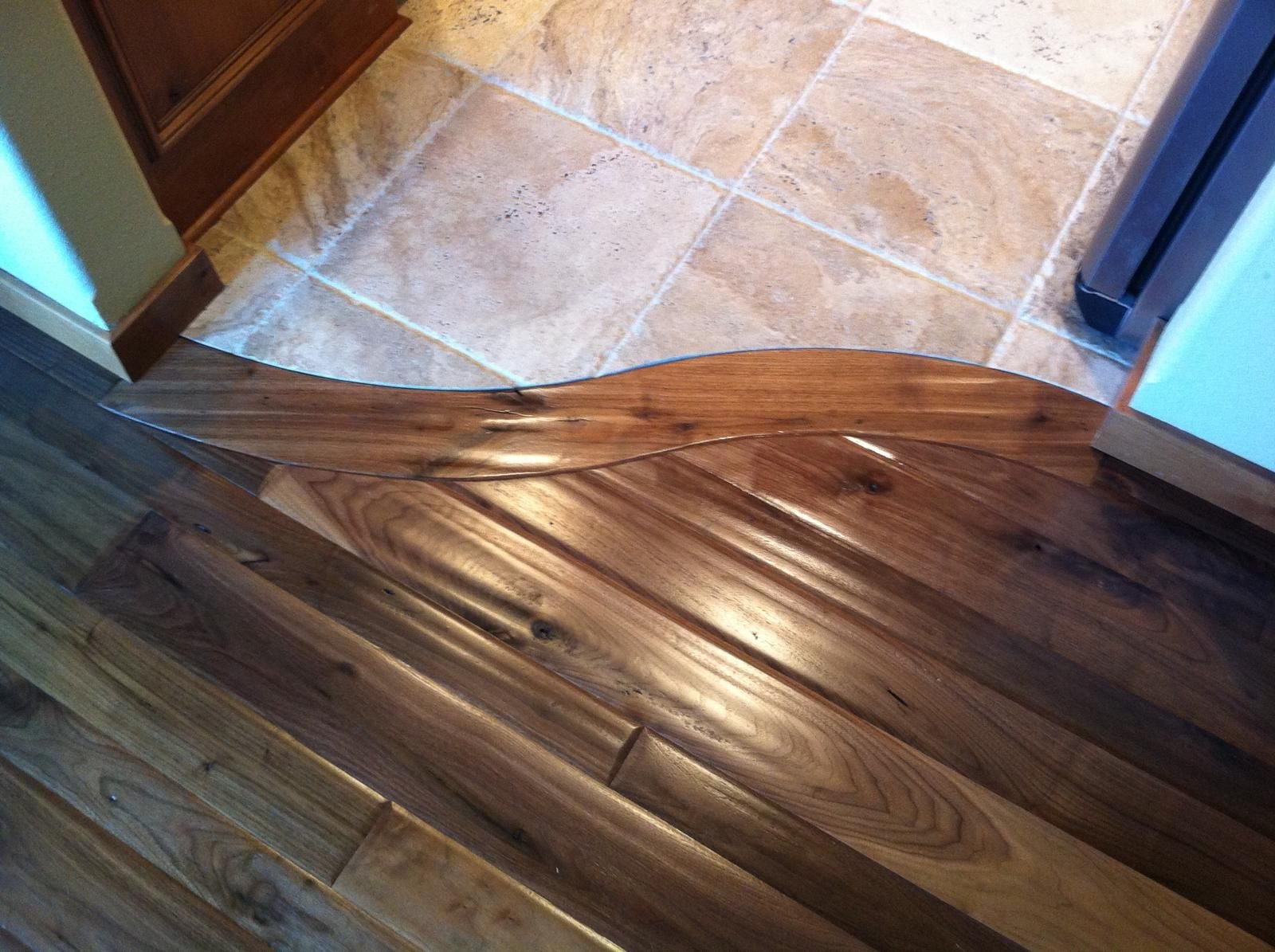 Curved wood-to-stone transition cut to an S-curve without a metal strip — walnut and travertine, custom commission