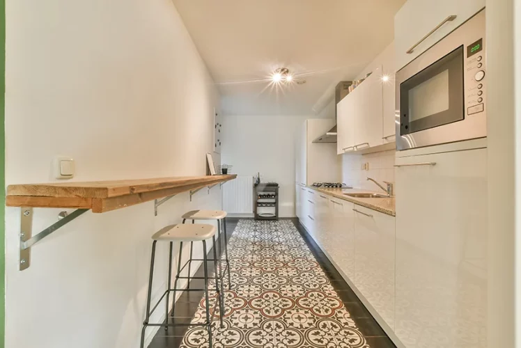 Long white kitchen with a refined patterned wood floor