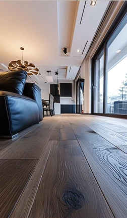 Restored dark hardwood floor running through a modern living room with floor-to-ceiling windows