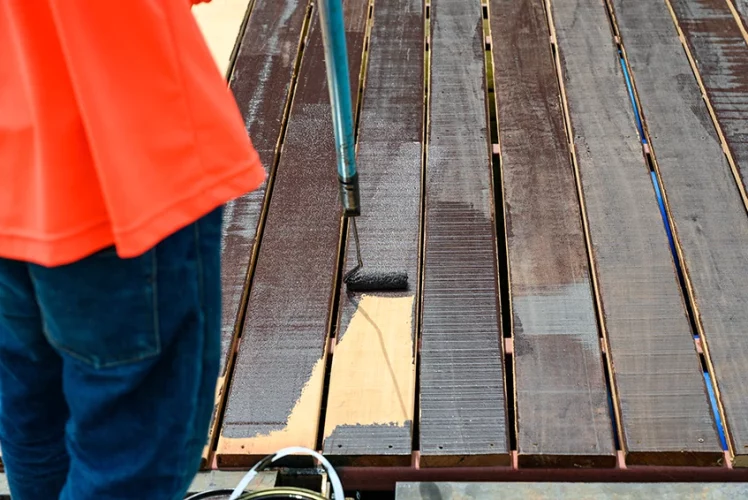 Worker applying finish to a wood floor with a roller