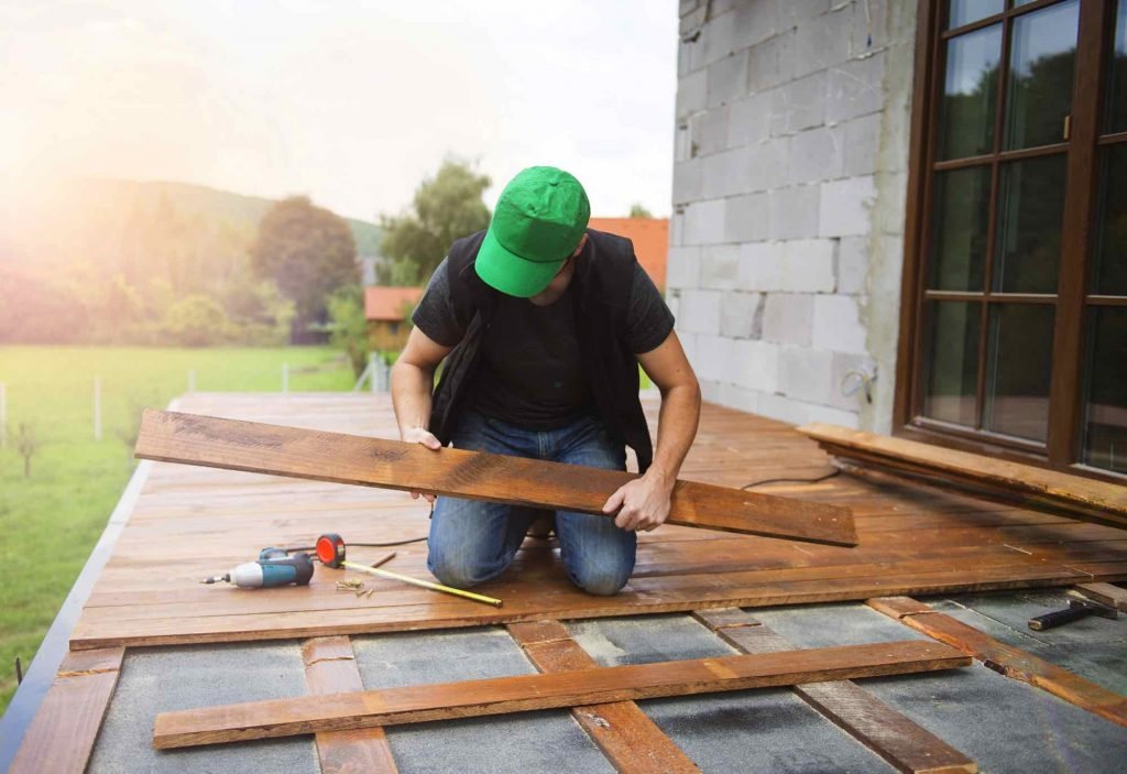 Installer fitting hardwood planks on a sunlit outdoor deck
