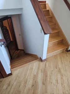 Wood staircase with a light oak floor at its base, installed by AG Floor Covering